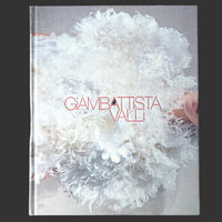 The cover of the book 'Giambattista Valli' featuring a monochrome photograph of a white, feathery-textured garment, with the title 'GIAMBATTISTA VALLI' prominently displayed.